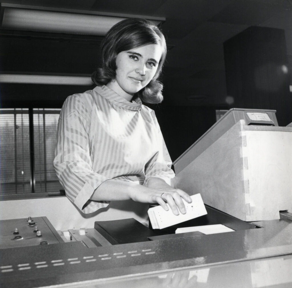A LEO woman operating LEO III equipment, looking at camera circa 1960